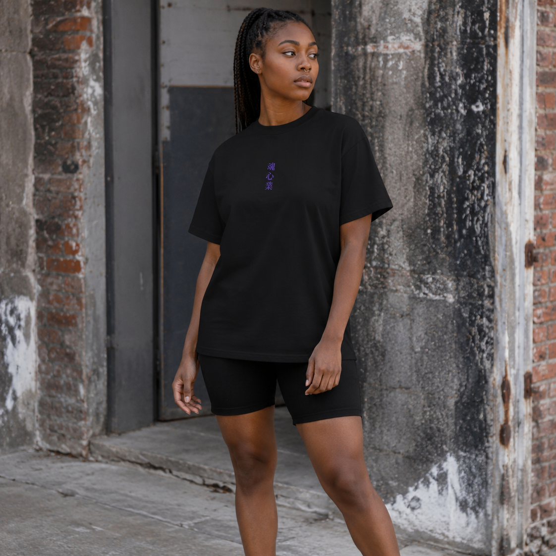 Woman wearing a black Soul & Hands T-shirt with small vertical purple Japanese kanji lettering on the front.