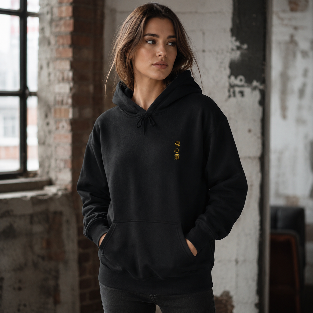 Woman wearing a black Soul & Hands hoodie with small vertical gold Japanese kanji lettering on the chest.