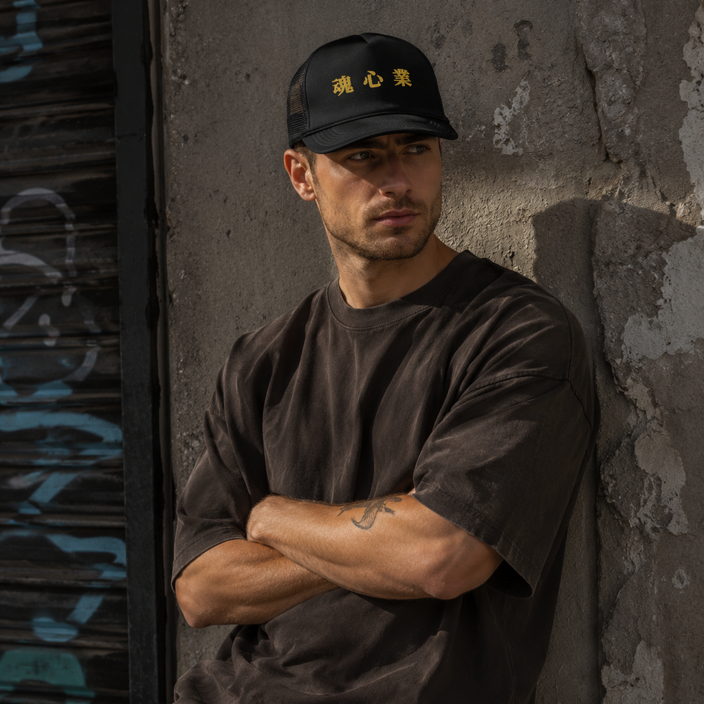 Man wearing a black Soul & Hands trucker cap with bold gold Japanese kanji lettering.