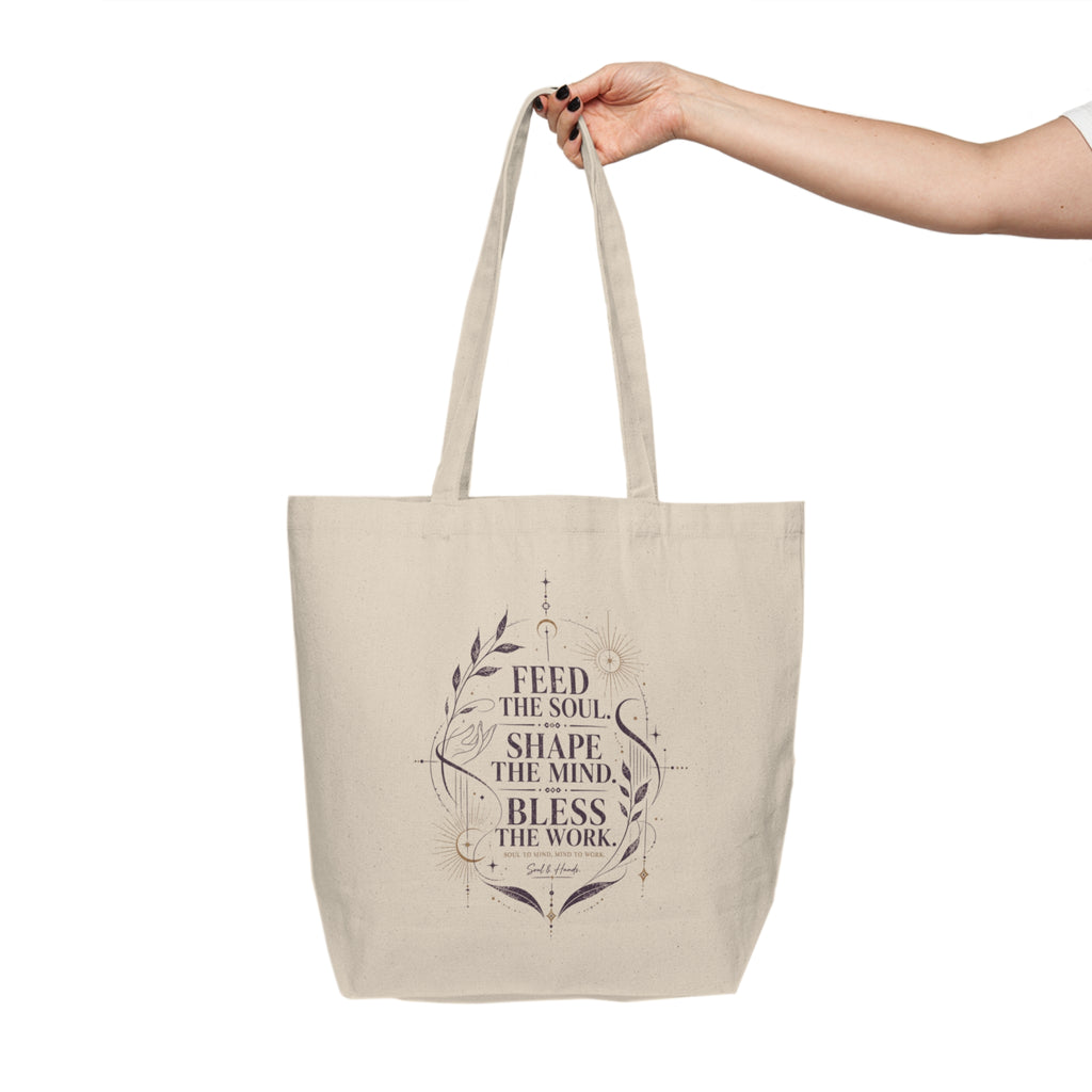 Beige tote bag with motivational quote held by a hand on a white background