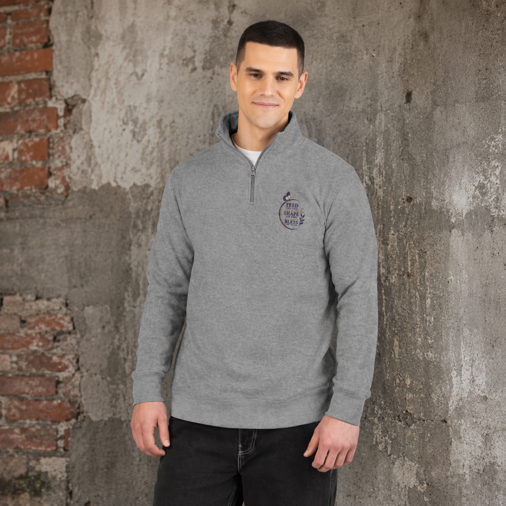 Man wearing a grey Soul & Hands quarter-zip sweatshirt with a small purple Feed, Shape, Bless chest emblem.
