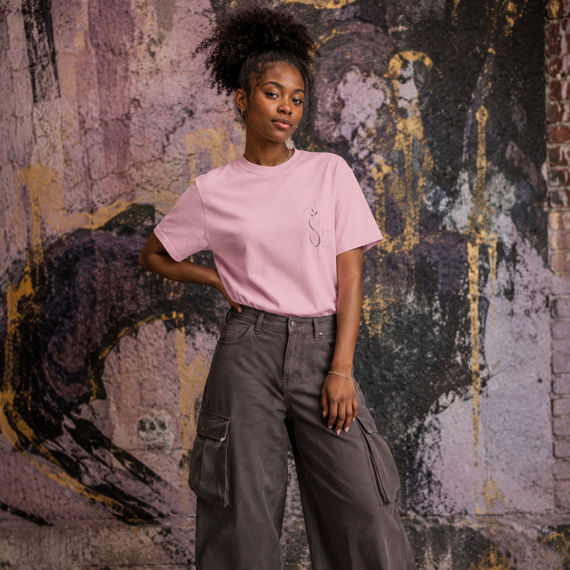 Woman wearing a pink Soul & Hands T-shirt with a small botanical infinity emblem on the left chest.
