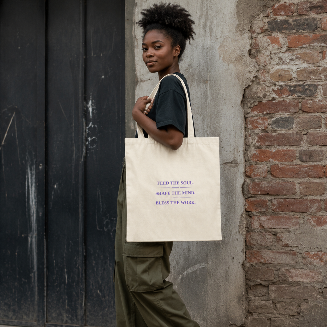 Woman carrying a natural Soul & Hands canvas tote with purple Feed the Soul, Shape the Mind, Bless the Work text.