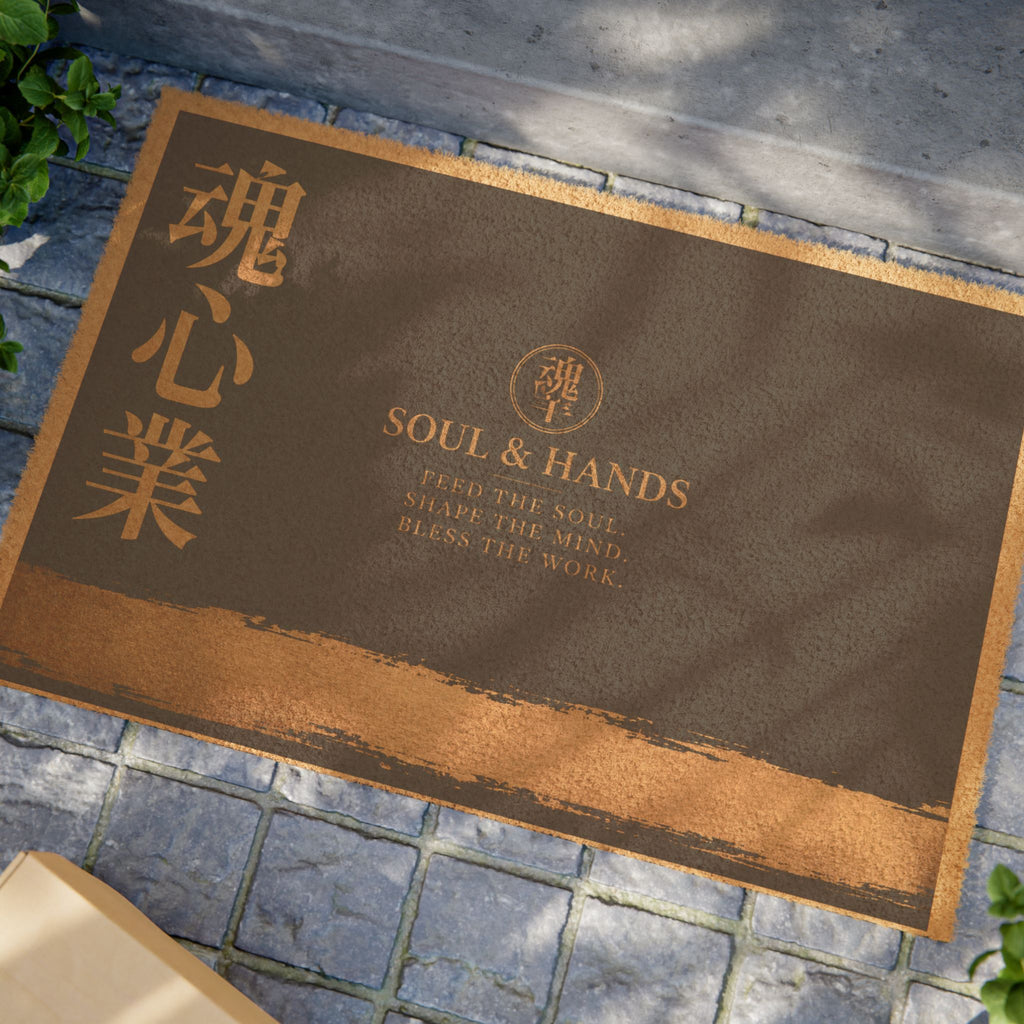 Brown doormat with 'Soul & Hands' branding on a stone pavement.